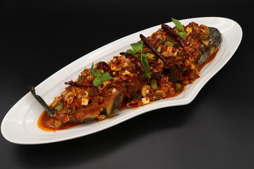 Thai spicy fried fish with herbs and chili on white plate