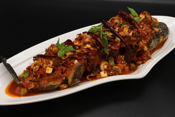 Thai spicy fried fish with herbs and chili on white plate