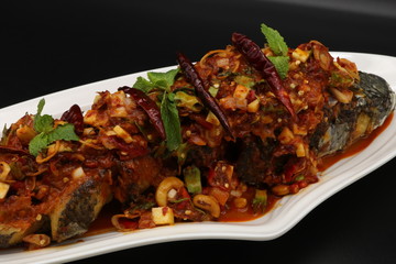 Thai spicy fried fish with herbs and chili on white plate