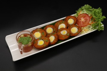 steamed fish with curry paste and egg inside on white plate with sauce and vegetables