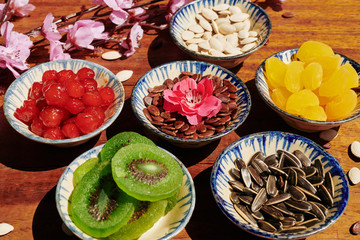 Delicious dried fruits and berries in small ceramic bowls on table prepared for Chinese New Year