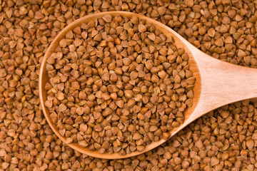  Raw buckwheat in a wooden spoon
