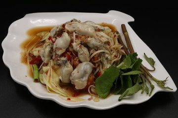 Somtum (Thai spicy salad) with oyster and vegetable in white plate