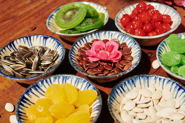 Small ceramic plates with sweet dried fruits and seeds on wooden table