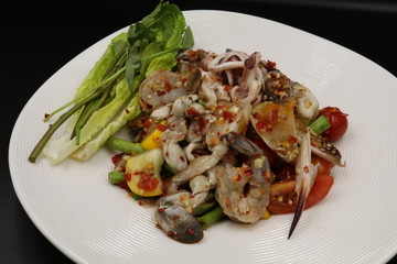 Somtum (Thai spicy salad) with raw prawn and raw crab in white plate