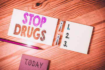 Conceptual hand writing showing Stop Drugs. Concept meaning put an end on dependence on substances such as heroin or cocaine Colored crumpled papers wooden floor background clothespin