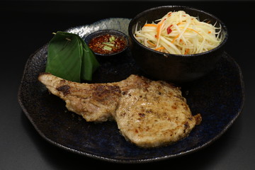 Grilled pork chop black pepper steak with somtum and Tha ispicy sauce on black plate