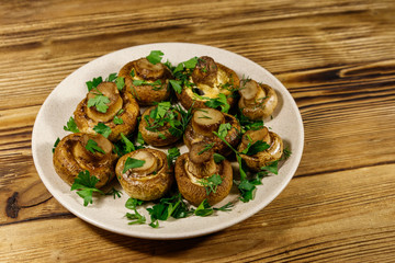 Baked mushrooms in plate on wooden table