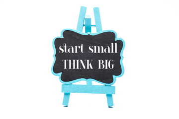 Blue frame blackboard with START SMALL THINK BIG motivational quote. Isolated on a white background.