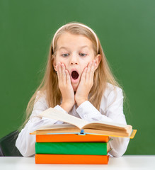 Shocked girl looks at book in classroom