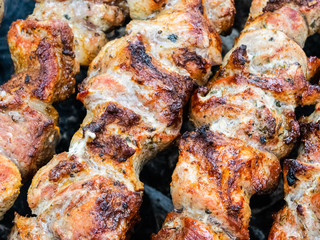 Frying pork on a skewer over a brazier. Turning meat over coals. Appetizing shish kebab.