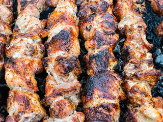 Frying pork on a skewer over a brazier. Turning meat over coals. Appetizing shish kebab.