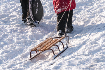kids going up on a hill pulling a yellow sledge.