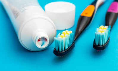 Toothbrushes with tube of toothpaste on blue background. Close up.