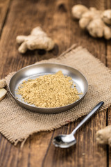 Some Ginger Powder on a vintage wooden table (selective focus; close-up shot)