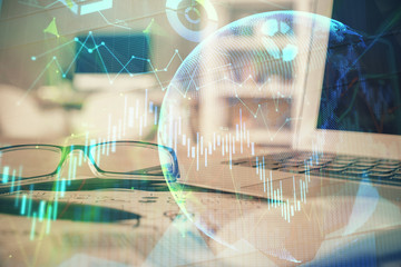 Financial chart hologram with glasses on the table background. Concept of business. Double exposure.