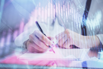 Double exposure of hands making notes with forex chart huds. Stock market concept.