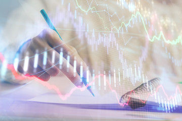 Financial forex graph displayed on hands taking notes background. Concept of research. Double exposure