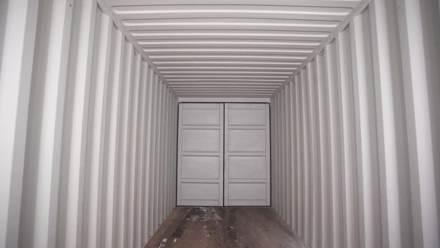 Inside large shipping container. Stock footage. View from inside locked cargo container with white striped iron walls. Empty light and locked cargo trailer container