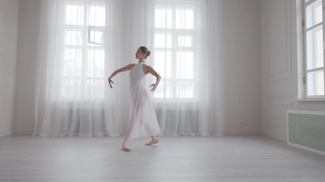 Graceful girl dancing classical ballet in a bright hall