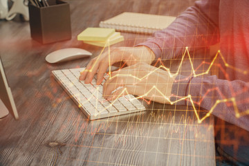 Stock graph with businessman typing on computer in office on background. Concept of analysis. Double exposure.