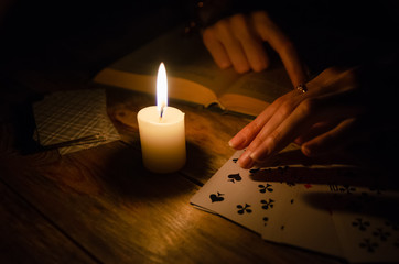 Cards, a book, a candle, a hand on a wooden table. study of magic. concept of divination, magic.