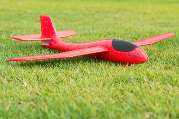 Red foam glider plane on the green grass. 