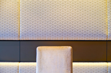 White backrest of chair in formal restaurant with white fabric and texture wall covering on...