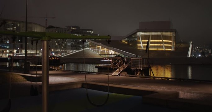 Wide angle 4K shot with parallax slow motion of illuminated Opera Theatre and Edvard Munch Gallery Lambda with gold reflections in fjord, in Bj&oslash;rvika Oslo Norway. Shot on professional cinema camera.