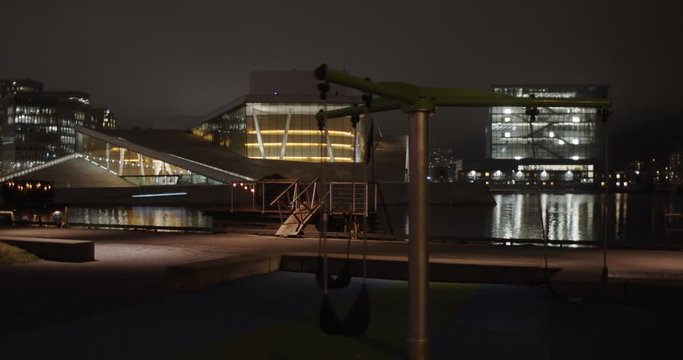 Cinema camera wide angle 4K shot with slow parallax motion of the illuminated Opera House theatre and Edvard Munch gallery Lambda with empty dark playground in front, at night in Bj&oslash;rvika Oslo Norway.