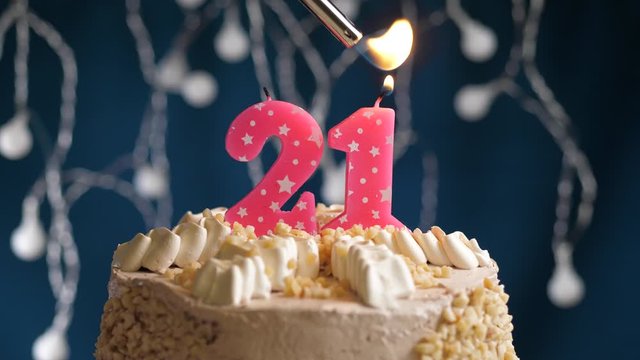 Birthday cake with 21 number pink candle on blue backgraund. Candles are set on fire. Slow motion and close-up view