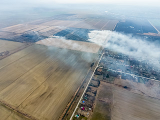 Fototapeta premium Top view of the small village. Smoke from the burning of straw i