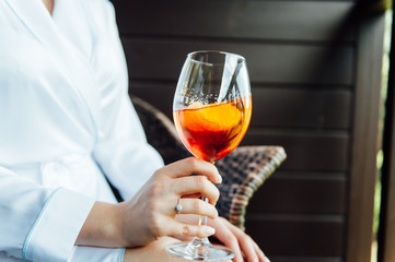 sexy woman holding a glass with aperol cocktail and smiling in the sun