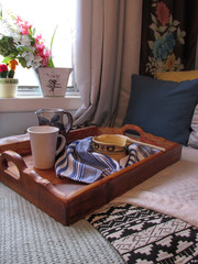 Breakfast served on a wooden tray and delivered to a bedroom. The bedroom has healthy amount of sunlight coming through the window