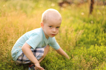 little boy sitting on green grass in the park