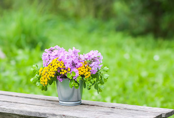 Beautiful bouquet of wildflowers on wooden bench on summer nature background in countryside