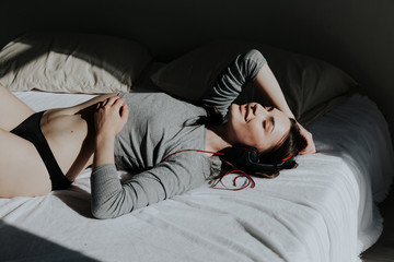 the woman listens to music in headphones dancing on the bed