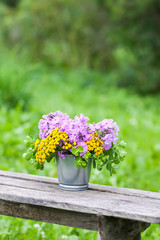 Beautiful bouquet of wildflowers on wooden bench on summer nature background in countryside