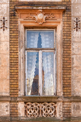 Exquisite window with white curtains of old decayed building in historic center of Lviv, Ukraine