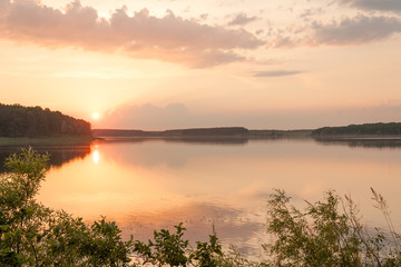 Fototapeta na wymiar Sunset over tranquil waters of picturesque lake surrounded by forest in Zhytomyr region, Ukraine