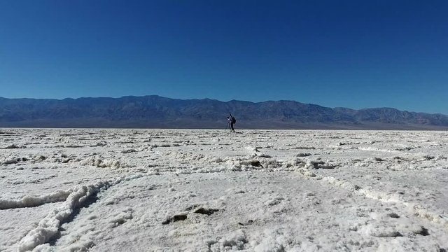 Professional female journalist shooting scenic wild nature of Badwater basin national park, videographer taking photos of arid standing near tripod in Death Valley at morning time enjoying hobby