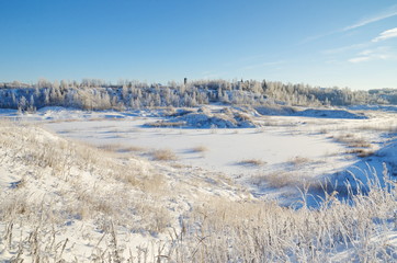 Winter rural landscape with a view of a frozen pond