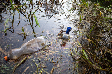 carelessly discarded plastic bottles and glass liquor bottles float in a lake