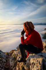 woman sitting on the peak of mountain and look on the nice fog view. Concept freedom.