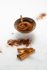 Cinnamon powder in bowl and sticks