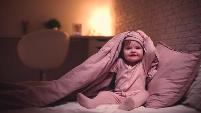 adorable little baby girl playing hide and seek in bed before going to sleep