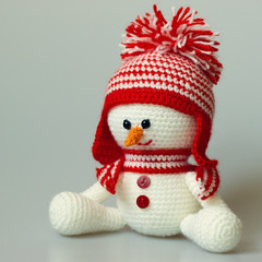 Handmade knitted toy snowman in a red hat and a scarf