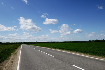 open road flanked by fields in late spring early summer