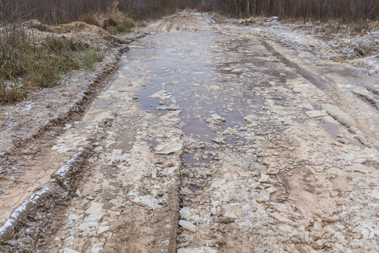 The bad ground or soil rural or suburb winter road or way with ice, snow, puddles, pools, mud and slush