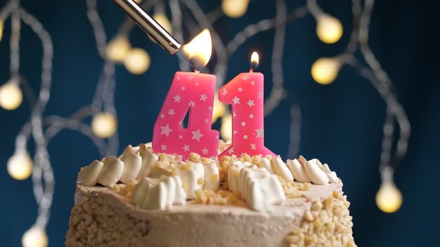 Birthday cake with 41 number pink candle on blue backgraund. Candles are set on fire. Slow motion and close-up view